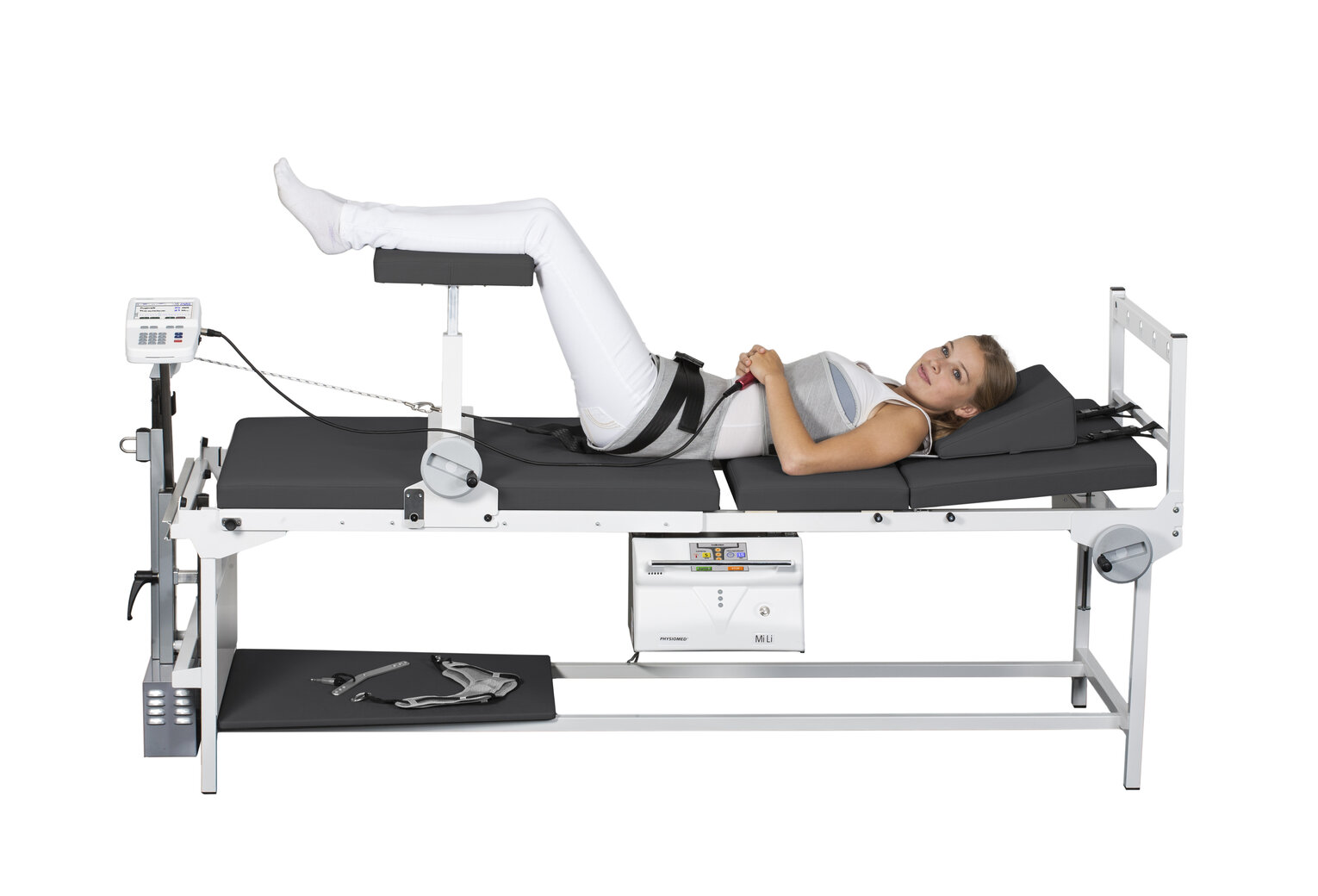 Lumbar Traktion Frau liegt auf medizinischem Behandlungstisch mit angehobenen Beinen, Gurt um Taille, vorbereitet für physiotherapeutische oder orthopädische Untersuchung.